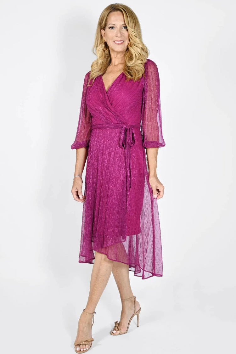 Frank Lyman Fuchsia Dress  Style: 232165  Experience the glamorous style of the Frank Lyman Fuchsia Dress. This luxurious wrap style dress features a deep fuchsia hue, sparkling mesh and glitter, plus a puffy sleeve design for added dazzle. The high low hem and wrap v-neck bring the perfect finishing touch. Perfect for those special occasions when you want to sparkle.  For best fit please refer to this size guide.