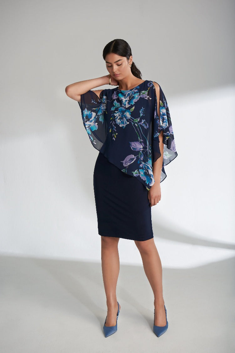 Joseph Ribkoff's Floral Overlay Dress is perfect for an intimate spring wedding! This dress features a lovely asymmetrical floral overlay with elements of turquoise, lavender and blue. The higher neckline is balanced with a sultry cold shoulder peekaboo detail.