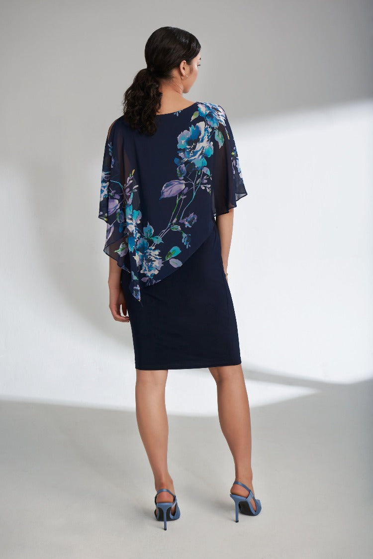 Joseph Ribkoff's Floral Overlay Dress is perfect for an intimate spring wedding! This dress features a lovely asymmetrical floral overlay with elements of turquoise, lavender and blue. The higher neckline is balanced with a sultry cold shoulder peekaboo detail.
